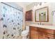 Well-lit bathroom featuring granite countertops, dark wood cabinets, a shower with curtain, and neutral tile flooring at 1052 Dees Dr, Oviedo, FL 32765