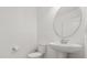 Elegant half bath with a pedestal sink, toilet, and a round mirror adding to the minimalist design at 14154 Shocklach Dr, Winter Garden, FL 34787
