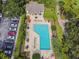 Aerial view of community pool with chairs, tables and umbrellas surrounded by green hedges and a parking lot at 333 La Creek Ct, Debary, FL 32713