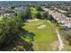 Aerial view of a lush golf course featuring a green, sand traps, and a small pond in a residential community at 333 La Creek Ct, Debary, FL 32713