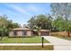 Inviting single-story home featuring a two-car garage, manicured lawn, and mature trees at 100 Des Pinar Ln, Longwood, FL 32750