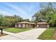 Single-story home with a well-maintained lawn, mature trees, and an attached two-car garage on a sunny day at 100 Des Pinar Ln, Longwood, FL 32750