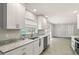 Bright kitchen featuring white cabinets, granite countertops, stainless dishwasher, and view to living area at 100 Des Pinar Ln, Longwood, FL 32750