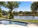 Pool with lake view, surrounded by lush trees and black iron fence at 1017 American Beauty St, Orlando, FL 32818