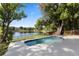 A clean and inviting pool overlooks a peaceful lake surrounded by mature trees and blue skies at 1017 American Beauty St, Orlando, FL 32818