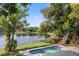 A refreshing pool is set against a tranquil lake backdrop with mature trees surrounding the property at 1017 American Beauty St, Orlando, FL 32818