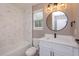 Beautiful bathroom featuring a white marble wall, round mirror and vanity with modern black hardware at 1340 Crystal Lake E Ave, Orlando, FL 32806