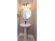 Stylish powder room with a pedestal sink, round mirror, and modern lighting fixtures at 1340 Crystal Lake E Ave, Orlando, FL 32806