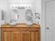 Bathroom featuring double sinks on a butcher block counter, wood cabinets and oval mirrors at 1430 Clarks Summit Ct, Orlando, FL 32828