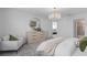 Bright bedroom with stylish chandelier, accent chair, and round mirror over modern dresser at 16164 Palm Frond Ave, Clermont, FL 34714