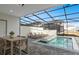 Screened in pool area with sun loungers and a dining table offers outdoor relaxation and entertainment at 16164 Palm Frond Ave, Clermont, FL 34714