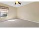 This bedroom has neutral carpet, a ceiling fan, and a sunlit window at 1842 Turnbull Lakes Dr, New Smyrna Beach, FL 32168