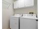 Bright laundry room featuring a white washer, dryer, and overhead cabinets at 1842 Turnbull Lakes Dr, New Smyrna Beach, FL 32168