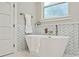 This bathroom features a standalone tub, wave tile accent wall and white door at 2306 Hargill Dr, Orlando, FL 32806