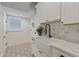 Bright laundry room featuring white cabinets, marble countertops, a farmhouse sink and stylish tile floors at 2306 Hargill Dr, Orlando, FL 32806