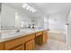 Bright bathroom featuring a double vanity, soaking tub, and glass-enclosed shower at 239 Longhirst Loop, Ocoee, FL 34761