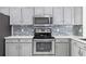 Kitchen featuring stainless steel oven, microwave, modern backsplash, and quartz countertops at 239 Longhirst Loop, Ocoee, FL 34761