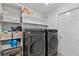 Laundry room featuring front loading washer and dryer, shelving, and a door at 239 Longhirst Loop, Ocoee, FL 34761