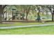 Community playground with slides and swings is shaded by mature trees and surrounded by green grass at 239 Longhirst Loop, Ocoee, FL 34761