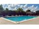 Large community pool with lounge chairs, tables, and chairs surrounded by green trees at 239 Longhirst Loop, Ocoee, FL 34761