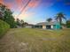 Expansive backyard with green lawn, mature trees, and a screened porch extending from the turquoise home at 2558 Academy Ave, Deltona, FL 32738