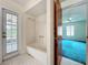 Bathroom with white tub, door to the outside and view of bedroom at 2558 Academy Ave, Deltona, FL 32738
