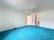 Bedroom with white walls, ceiling fan, blue carpet, and doorway to another room at 2558 Academy Ave, Deltona, FL 32738