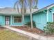 Charming turquoise home featuring a well-maintained walkway and tropical landscaping with palm trees at 2558 Academy Ave, Deltona, FL 32738