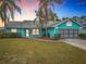 Charming single-story home with a vibrant turquoise exterior, well-maintained lawn, and mature palm trees at 2558 Academy Ave, Deltona, FL 32738