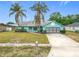 Bright turquoise single-story home with a gray roof, complemented by palm trees and a lush green lawn at 2558 Academy Ave, Deltona, FL 32738