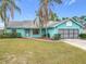 Charming single-story home with a vibrant turquoise exterior, well-maintained lawn, and mature palm trees at 2558 Academy Ave, Deltona, FL 32738