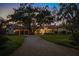 Elegant stucco home with a red tile roof, mature trees, a circular drive, and a spacious three-car garage at 3412 Lilas Ct, Windermere, FL 34786