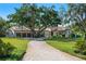 Elegant stucco home with a red tile roof, mature trees, a circular drive, and a spacious three-car garage at 3412 Lilas Ct, Windermere, FL 34786