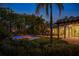 Backyard pool with vibrant landscape lighting and an expansive covered patio area with manicured foliage at 3412 Lilas Ct, Windermere, FL 34786