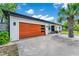 Modern home featuring a wooden garage door, white exterior, and lush landscaping with a palm tree at 532 Darcey Dr, Winter Park, FL 32792