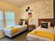 Charming ' bedroom featuring two twin beds with fun Mickey Mouse themed wall art at 5354 Diplomat Ct # 105, Kissimmee, FL 34746