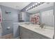 Well-lit bathroom with double vanity, decorative mirror, and a shower with floral curtain at 5388 Birchbend Loop, Oviedo, FL 32765