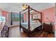 A spacious bedroom featuring a four-poster bed, hardwood floors, and a large window for natural light at 5388 Birchbend Loop, Oviedo, FL 32765
