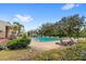 Community pool with lounge chairs surrounded by mature trees and lush landscaping under a blue sky at 5395 Emerald Isle Drive # 1011, Orlando, FL 32812