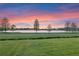 Picturesque view of a tranquil lake surrounded by lush green lawns and a colorful sunset sky at 5640 Brookline Dr, Orlando, FL 32819