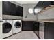 Modern laundry room with black cabinets, granite countertops, and stainless-steel appliances at 5640 Brookline Dr, Orlando, FL 32819