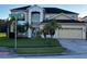 Inviting two-story home featuring a manicured lawn, mature palm trees, and a convenient two-car garage at 5803 Cheshire Cove Ter, Orlando, FL 32829