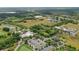 An aerial view showcases a lively community, with golf, tennis, a pool, businesses, and green spaces, under a sunny sky at 7130 Forty Banks Rd, Harmony, FL 34773