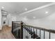 Well-lit staircase with wood treads and dark metal railing leading to a hallway with wood floors at 9250 Neher St, Orlando, FL 32827