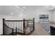 Well-lit staircase with dark metal railing leading to a living room with wood floors and a large television at 9250 Neher St, Orlando, FL 32827