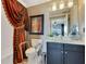 The well-lit bathroom includes a vanity, toilet with stability bars, and an elegant shower curtain at 100 S Eola Dr # 1102, Orlando, FL 32801