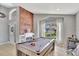 Stylish game room with pool table, brick accent wall, and bright natural light from the arched window at 11209 Taeda Dr, Orlando, FL 32832