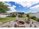 Well-manicured backyard with a stone fire pit, chairs, green landscaping and a covered patio at 116 Hurst Ct, Deland, FL 32724