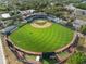 Aerial view of a baseball field with green grass, stadium seating, and surrounding trees in a neighborhood setting at 116 Hurst Ct, Deland, FL 32724