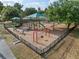 Community playground with slides, swings, and climbing structures on a mulch surface, surrounded by a black metal fence at 116 Hurst Ct, Deland, FL 32724